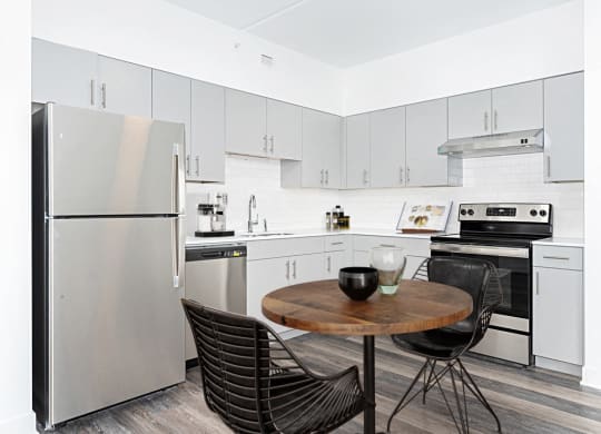 a kitchen with white cabinets and stainless steel appliances and a small table