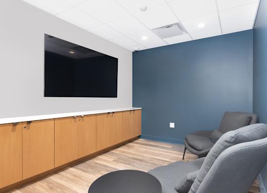 a waiting room with two chairs and a tv on the wall
