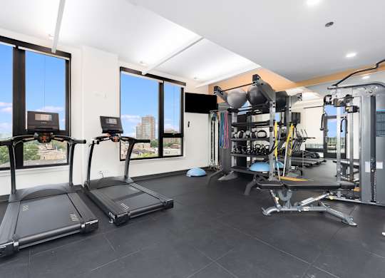 two treadmills and other exercise equipment in a gym with windows