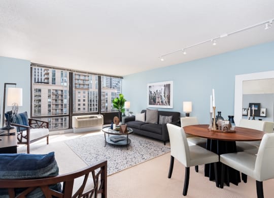 a living and dining room area with blue walls and a large window at Columbus Plaza, Chicago, Illinois