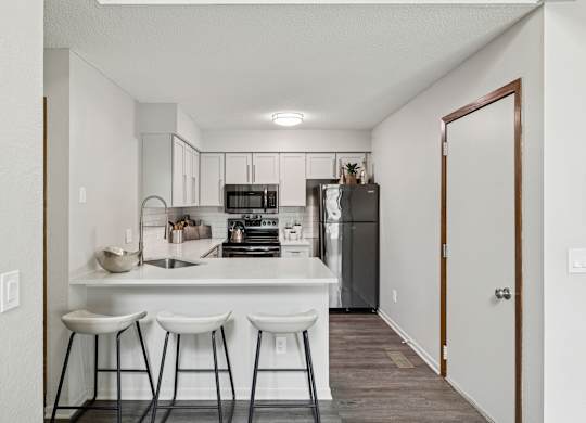 A kitchen with white countertops and bar stools at Seasons Villas Apartments, Minnesota, 55125