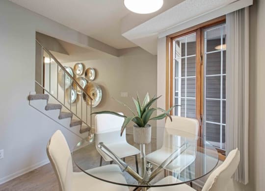 a dining room with a glass table and chairs at Seasons Villas, Woodbury Minnesota