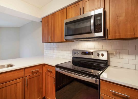 a kitchen with a stove and a microwave at Seasons Villas, Woodbury, 55125