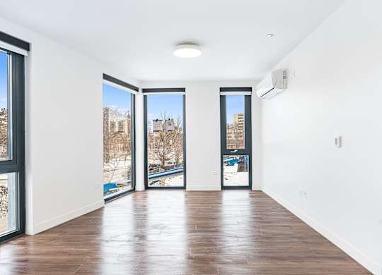 A room with a wooden floor and a view of a snowy landscape through the windows.