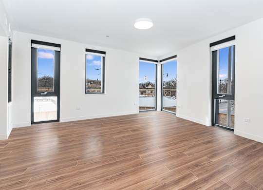 A room with wooden floors and three windows.
