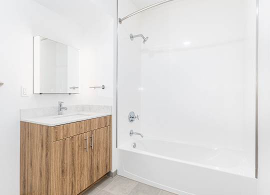 A white bathroom with a sink, mirror, and bathtub.