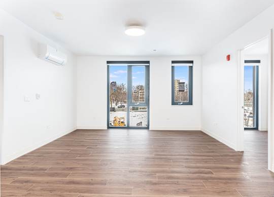 A spacious room with wooden floors and large windows.