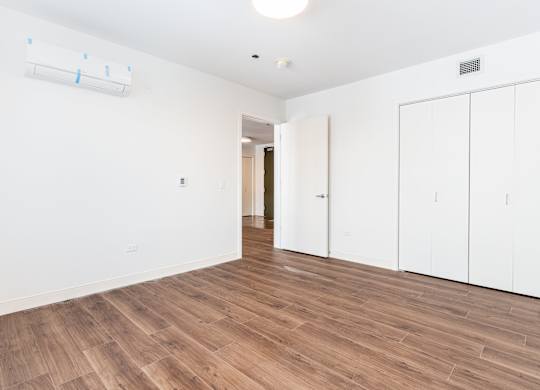 A room with wooden flooring and white walls.
