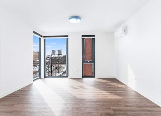 A room with a wooden floor and a view of a snowy landscape through the windows.