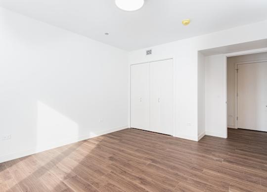 A room with a white wall and a wooden floor.