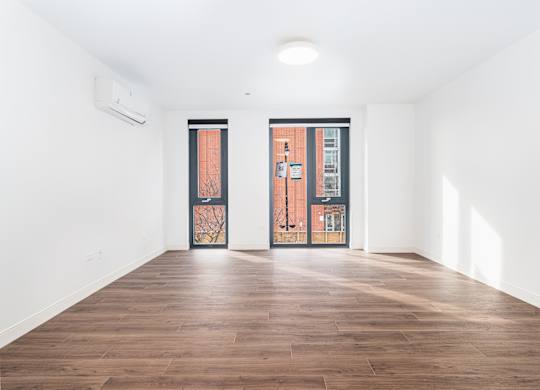 A room with a wooden floor and two doors.