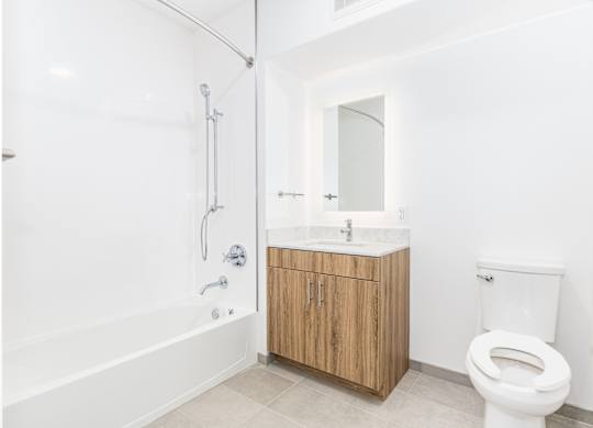 A white bathroom with a wooden cabinet and a white toilet.