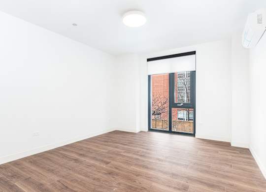 A room with wooden flooring and a sliding glass door.