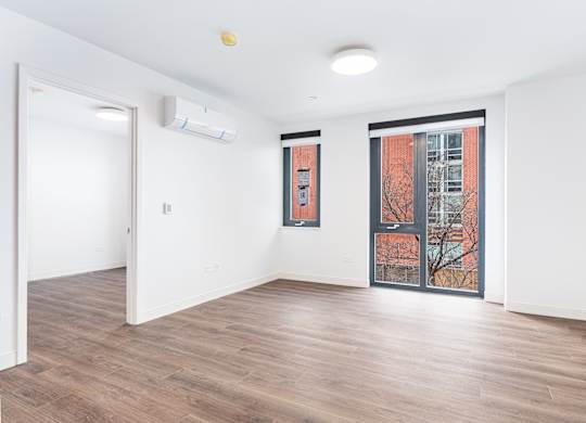 A room with a window showing a tree and a building outside.