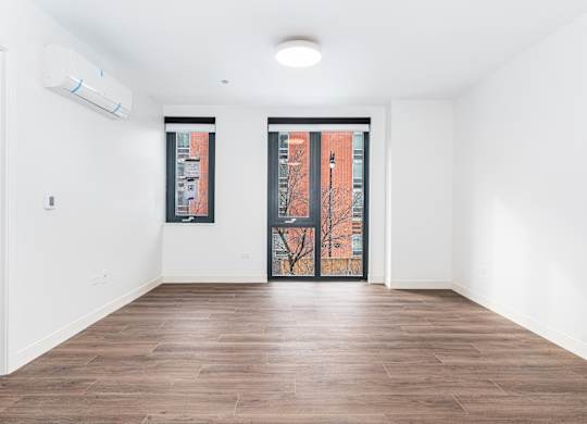A room with a brown floor and a white wall with a window.