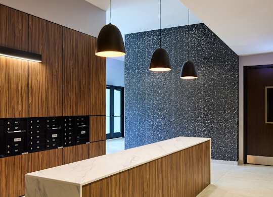 Modern lobby with wood reception desk and pendant lighting at Thrive Exchange Apartments, Illinois, 60617