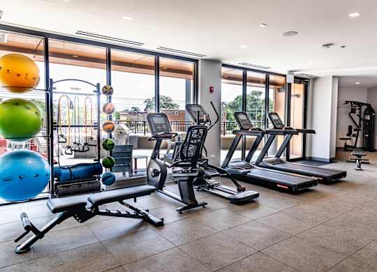 Fitness center with cardio equipment and outdoor terrace at Thrive Exchange Apartments, Chicago, IL 60617