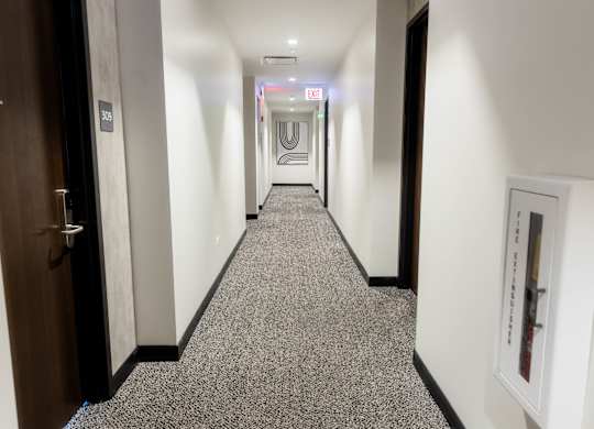 Hallway with carpeted flooring and fire extinguisher at Thrive Exchange Apartments, Chicago, 60617