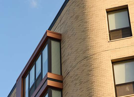 Curved brick building facade with contemporary windows at Thrive Exchange Apartments, Chicago, IL