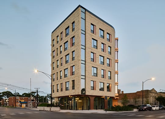 Six story brick building at dusk with arched storefronts at Thrive Exchange Apartments, Illinois