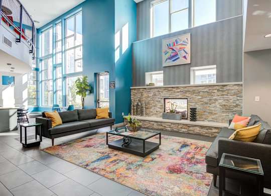 A living room with a grey couch and a colorful rug.