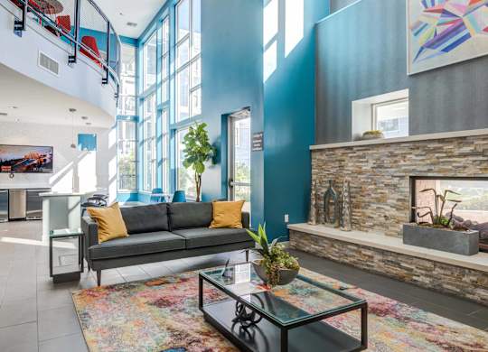 A living room with a grey couch and a glass coffee table.