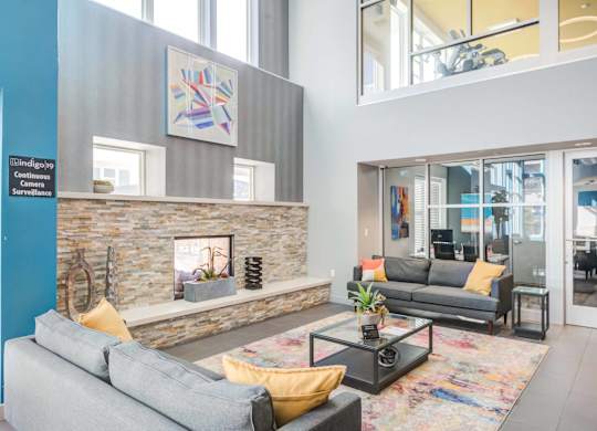 A living room with a grey couch and a stone fireplace.
