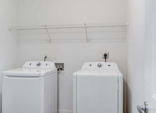 Two white washing machines in a small laundry room.