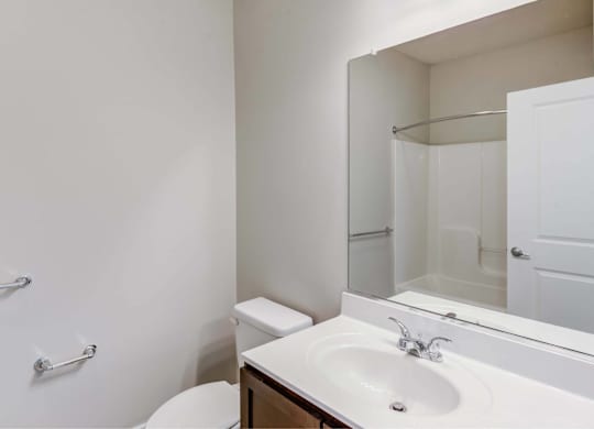 A white bathroom with a toilet, sink, and shower.