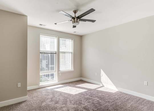 A room with a ceiling fan and a window with blinds.