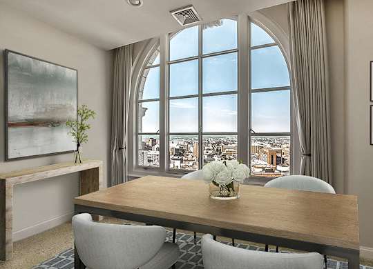 A dining room with a table, chairs, and a view of the city through large windows.