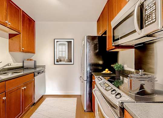 A kitchen with a refrigerator, microwave, and oven.