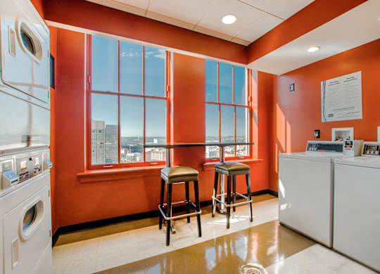 A laundry room with orange walls and a window.
