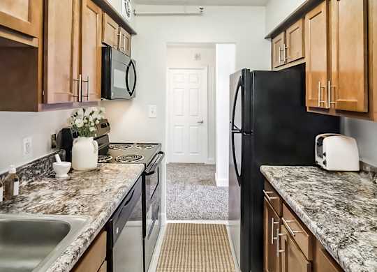 A kitchen with a black refrigerator and wooden cabinets.