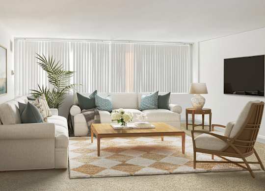 A living room with a white couch, a wooden coffee table, and a large window with blinds.