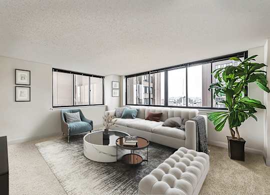 A living room with a white couch, a blue chair, a coffee table, and a plant.