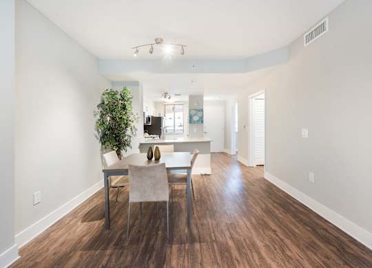 A dining room with a table and chairs and a potted plant.