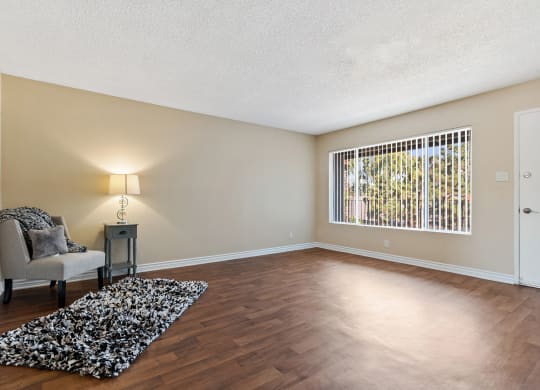 an empty living room with a chair and a rug at Terramonte Apartment Homes, Pomona, CA
