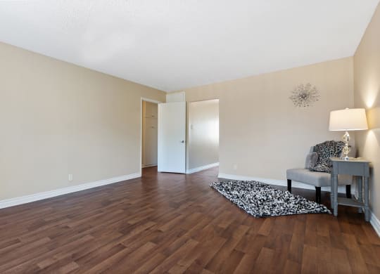 an empty living room with hard wood flooring and a chair and table at Terramonte Apartment Homes, Pomona, California