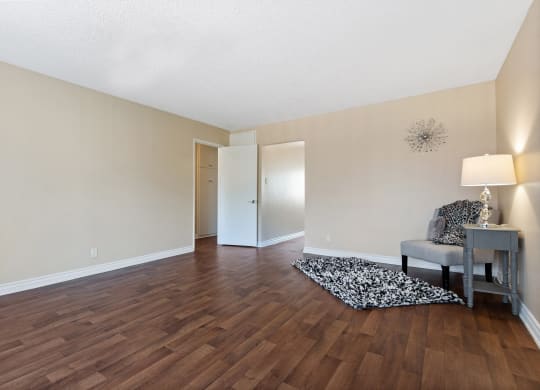an empty living room with hard wood flooring and a chair and table at Terramonte Apartment Homes, Pomona, California