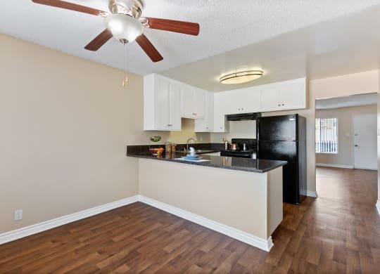 an open living room with a kitchen and a ceiling fan at Terramonte Apartment Homes, Pomona, California