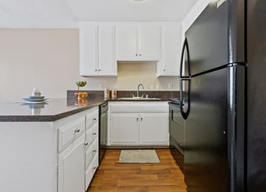 a kitchen with white cabinets and a black refrigerator at Terramonte Apartment Homes, Pomona