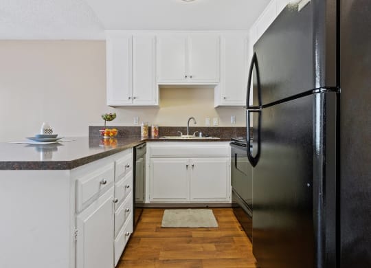 a kitchen with white cabinets and a black refrigerator at Terramonte Apartment Homes, Pomona