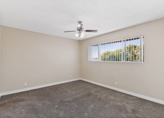 a small room with a window and ceiling fan at Terramonte Apartment Homes, Pomona, CA