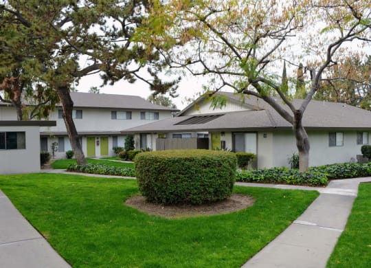 a white house with a lawn and trees in front of it at Terramonte Apartment Homes, Pomona, 91767