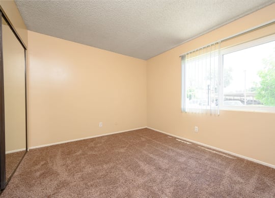 a bedroom with a large window and a carpeted floor at Oak Terrace Senior Apts, California
