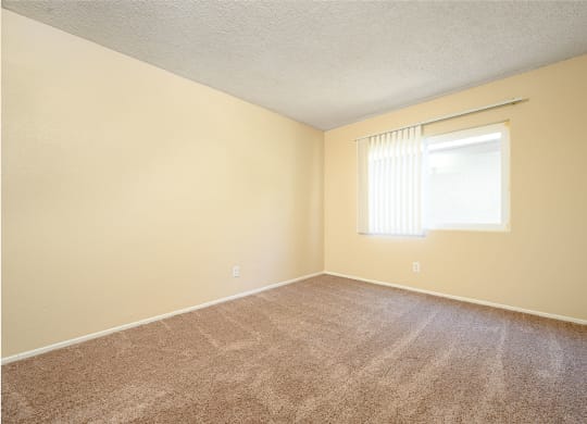 a bedroom with a window and a carpeted floor at Oak Terrace Senior Apts, California