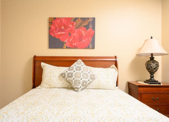 a bedroom with a bed and a nightstand with a lamp at Oak Terrace Senior Apts, Hemet, CA 92543