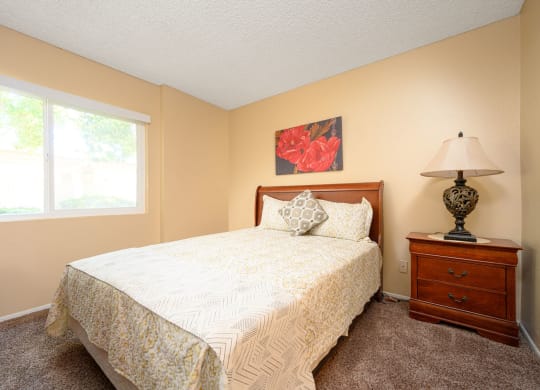 a bedroom with a bed and a nightstand at Oak Terrace Senior Apts, Hemet, 92543