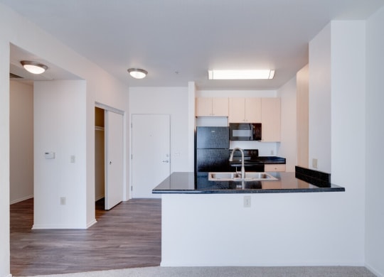 a kitchen with a black counter top and a sink at Helix at University Village, Pomona